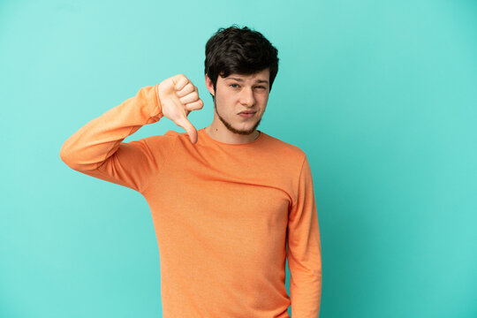 Young Russian man isolated on blue background showing thumb down with negative expression