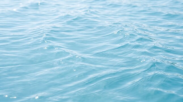 Gentle waves on clear blue water surface with soft light glimmer