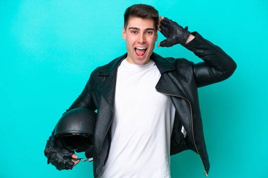 Young caucasian man with a motorcycle helmet isolated on blue background with surprise expression