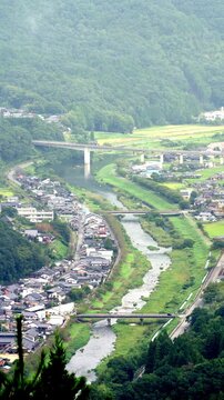 竹田城跡から望む円山川と赤いローカル線が走る麓の街並みの縦動画