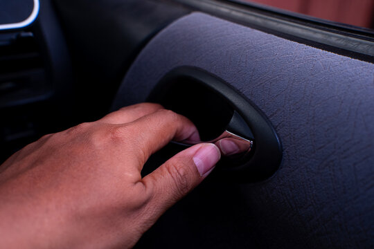 Passenger hand pulling chrome interior door handle mechanism to open the car door from inside.