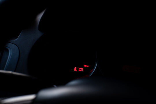 Glowing red oil level and battery warning indicator icons lit up on a dark car dashboard instrument cluster.