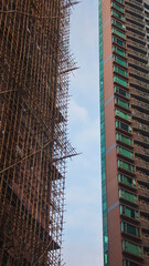 Contrast between an old scaffolding-covered building and a modern high-rise under a clear sky in Central, Hong Kong © MarieXMartin