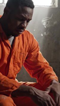 A Moment of Reflection: The Weight of Isolation Captured in a Solemn Portrait of a Man in an Orange Jail Suit, Struggling with His Thoughts Behind Bars