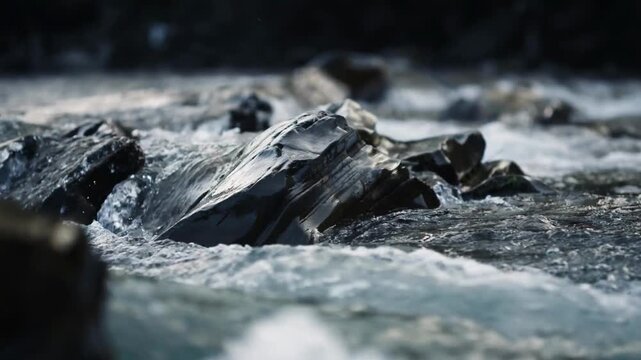 Water rushing over rocks in mountain stream. Rushing water cascading over Stones in mountain stream, surrounded by lush green grass along banks. scene captures beauty of nature. Clear flow ripple Wave