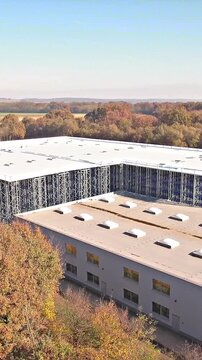 Flying towards a industrial warehouse being built in middle forest 