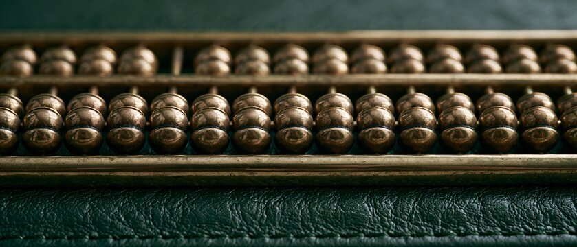 Antique brass abacus resting on a dark green leather blotter with cinematic ambient daylight