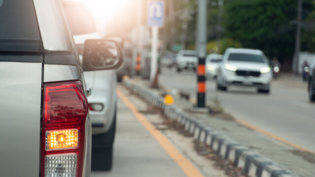 Rear view of pickup car with turn on right signal for U-Turn. Wait in a line of traffic on concrete road in a busy daytime. Median with light poles and cars are driving on the opposite side.