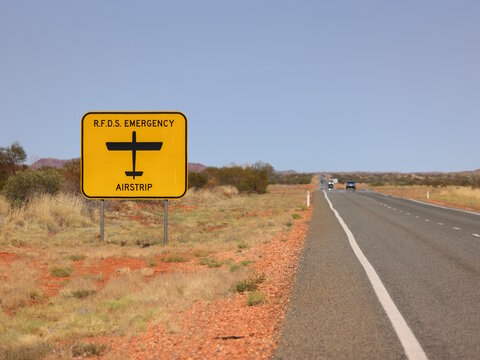 Yellow RFDS emergency airstrip road sign alongside a highway in Outback rural Australia. Alerting motorists to Royal Flying Doctor Service airplane landing zone. Copy space