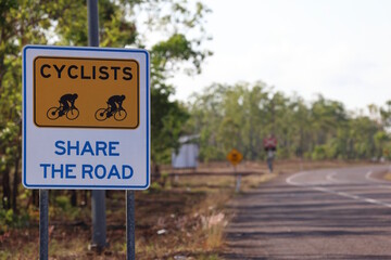 Cyclists share the road sign. Cautioning motorists to protect cycling safety on a rural highway with trees and plenty of copy space for road safety themes or transport messages in Australia © BJP7images