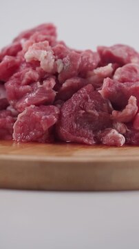 Close-up cinematic motion of raw diced beef chunks on a wooden cutting board, ready for cooking