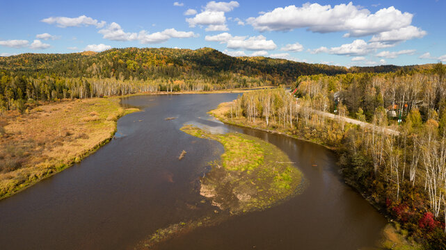 Aerial View of a Winding River Through Autumn Forest and Hills