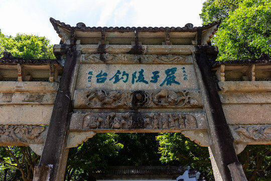 Ancient Stone Archway with Chinese Inscriptions and Carvings in a Park
