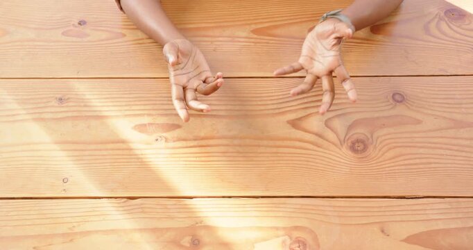 African American person resting hands on wooden table, wearing stylish watch