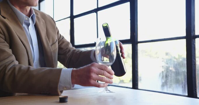 Businessman enjoying red wine tasting near large window in modern office