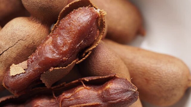 Close up of sweet and sour tamarind fruit pods in a white bowl for cooking