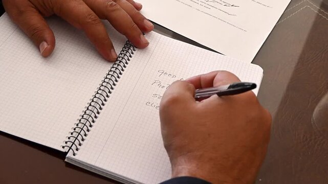 Male hands writing a to-do list on a notepad