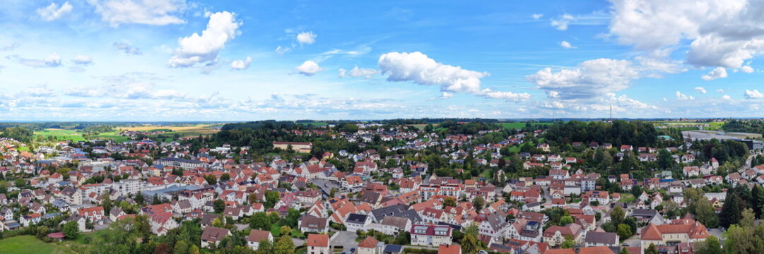 Weites Luftbild-Panorama von Ochsenhausen in Oberschwaben mit Blick &uuml;ber die Stadtstrukturen und Wohngebiete, umgeben von gr&uuml;ner Natur unter blauem Sommerhimmel.