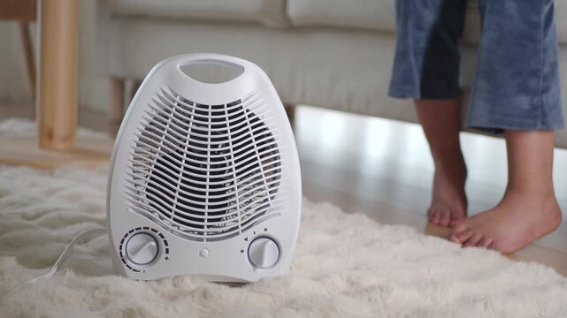 White electric fan heater blowing warm air in living room for child comfort during winter season