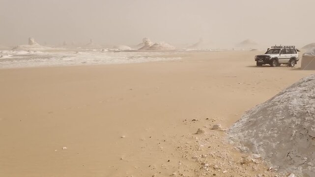 Off-road vehicle SUV and a big white tent against the backdrop of the white desert of Egypt during a dust storm,  slow movement