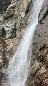 A high-action, close-up view of powerful water spray blasting off a rugged rocky ledge at a mountain waterfall in Khyber Pakhtunkhwa, Pakistan, September