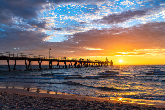 Glenelg Beach Jetty with people silhouettes at warm summer sunset, Adelaide, South Australia