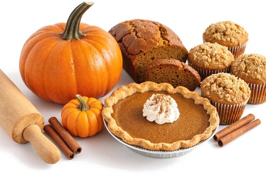 Freshly baked pumpkin pie with whipped cream and assorted fall baked goods and pumpkins