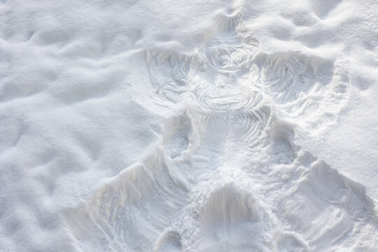 Snow angel imprint in fresh white snow, top view of winter fun and holiday season.