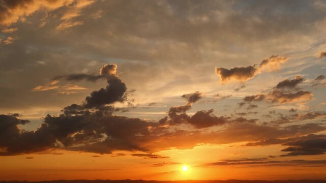Time lapse of a majestic golden sunset with illuminated moving clouds. A tranquil nature scenery with the glowing sun and pleasant warm colors.