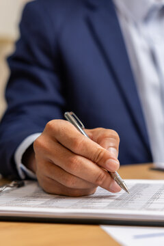 Businessperson writing document hand pen contract office signing businessperson writing document with pen during contract review office, conveying focused professional attention and formal
