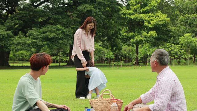 Happy mother and daughter, Happy Asian family having fun time on picnic at city nature park sunny day, outdoor activitie with daughter father, mother and grandfather