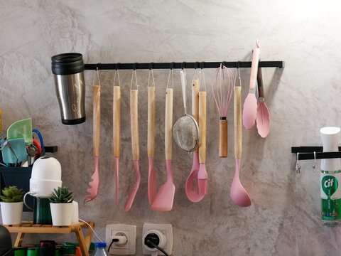 Ustensiles de cuisine roses suspendus sur une barre murale dans une cuisine moderne