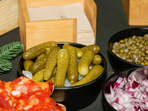 Cornichons, c&acirc;pres et oignons rouges servis comme condiments sur un buffet de charcuterie lors d&rsquo;un mariage