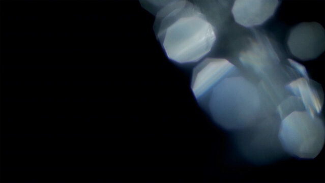 Blurred white hexagonal bokeh light orbs on a solid black background