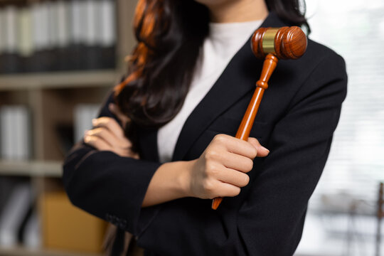 Young female lawyer holding gavel in legal office.