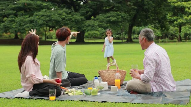 Slow motion hugging Happy father and daughter, Happy Asian family having fun time on picnic at city nature park sunny day, outdoor activitie with daughter father, mother and grandfather