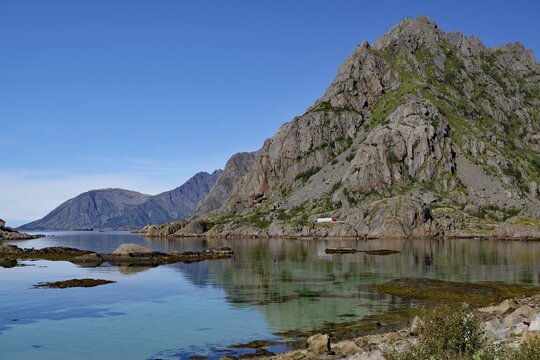 Shallow bay with crystal clear water in front of high mountain, Henningsvaer, Festv&aring;gtind, V&aring;gan municipality, Nordland province, Norway