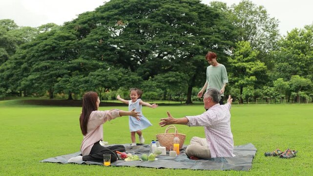 Slow motion hugging Happy mother and daughter, Happy Asian family having fun time on picnic at city nature park sunny day, outdoor activitie with daughter father, mother and grandfather