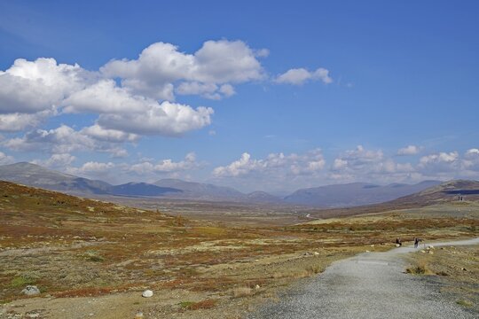 Hiking trail winds through a hilly landscape towards the mountains under a blue sky with clouds, autumn, Sn&ouml;hetta, Hjerkinn, Dovrefjell-Sunndalsfjella National Park, Norway