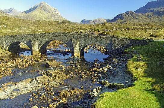 Historic stone bridge over a shallow river with mountains in the background, Slicgachan, Isle of Skye, Scotland, United Kingdom