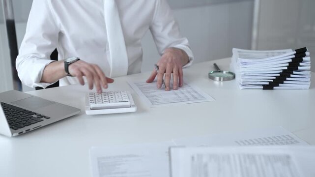 Accountant calculating tax, reviewing financial report, and managing business paperwork on a modern office desk, processing data for audit and budget planning. Audit and taxes