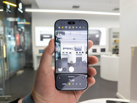 Poznan, Poland - September 19, 2026: Apple iPhone 18 Pro screen interface showing professional camera controls held by a person within a clean retail environment for mobile tech