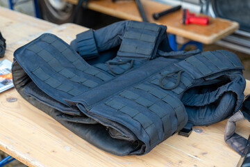 Obraz premium Tactical body armor vest lying on wooden workbench in workshop