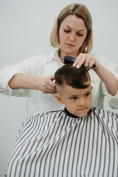 Little boy at the hairdresser. Hairdresser's hands making hairstyle to little boy, close up. Fashionable haircut for boy