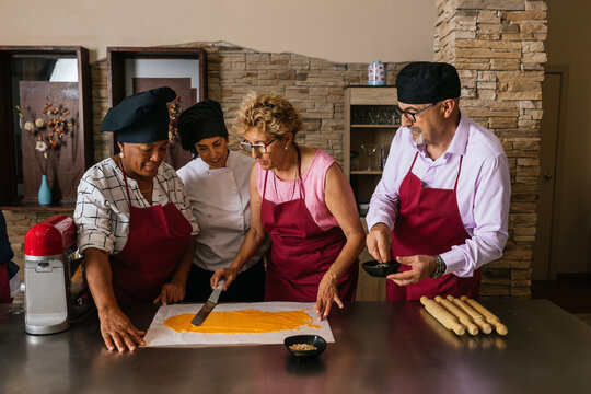 Chefs spreading dough during cooking course in restaurant kitchen