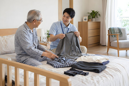 Elderly Japanese man choosing clothes with a male caregiver at home