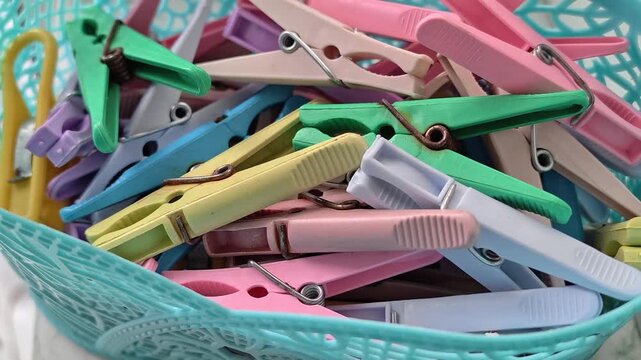 A colorful basket filled with lots of clothes pins
