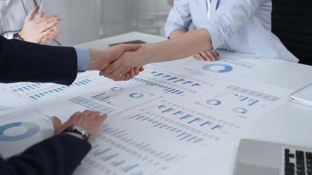Business executives shaking hands, sealing an agreement after successful negotiations in a bright office, symbolizing partnership, collaboration, and a mutually beneficial deal signing