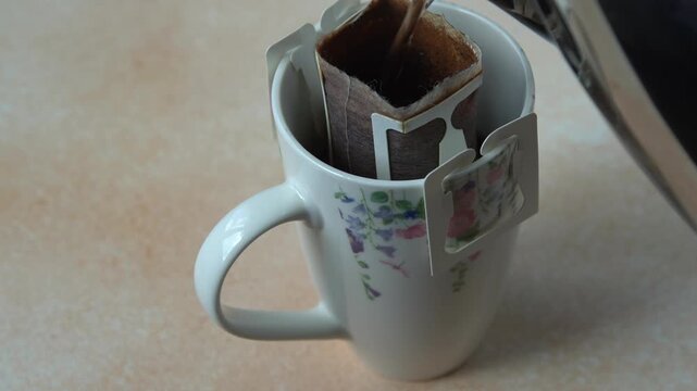 Pouring Hot Water into Drip Coffee Bag in Cup Close Up