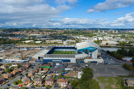 Aerial perspective capturing Elland Road football stadium, the historic home of Leeds United FC, showcasing the green pitch, Don Revie Stand, East Stand, and surrounding Beeston neighbourhoods